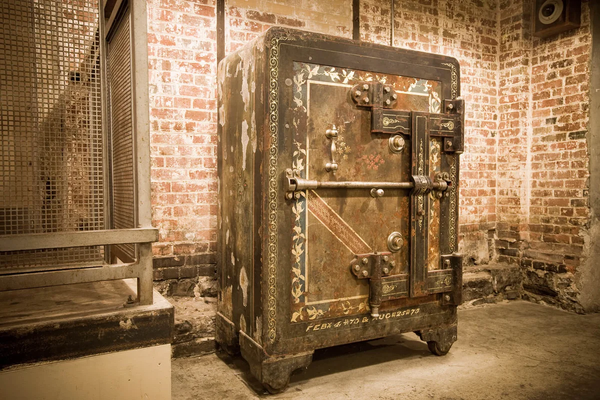 An ornate antique safe with exposed boltwork in a brick room